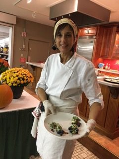 Photo of Chef Cathy Vogt in a kitchen holding a plate of nutritious food in the Hudson Valley New York