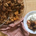 pecan peach crumble in a pie dish and in a white bowl served with ice cream