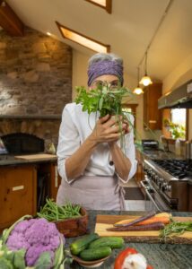 Cathy in a kitchen with a bunch of herbs
